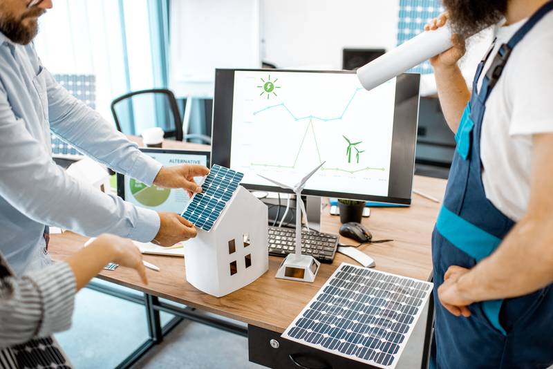 Equipe réfléchissant à l'installation de panneaux photovoltaïques sur une maquette