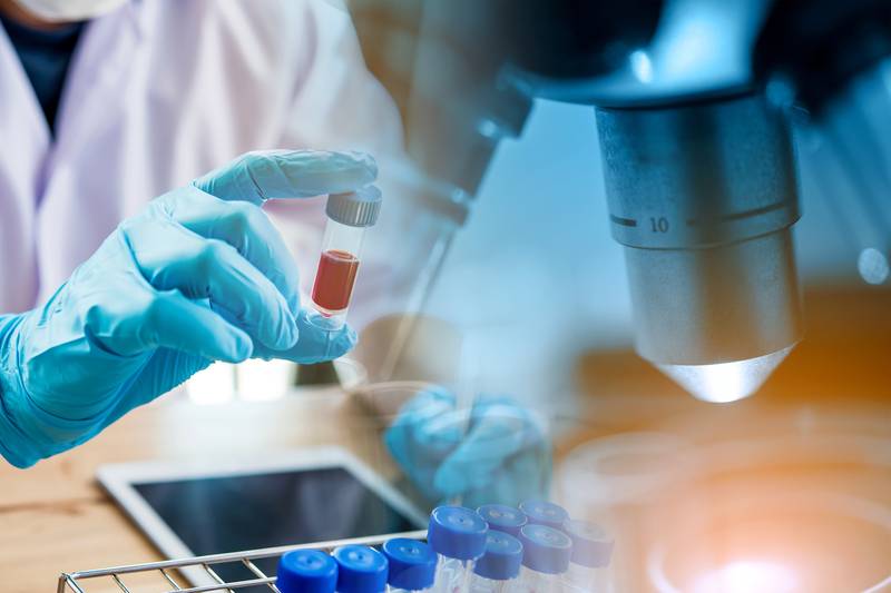 Scientifique avec une éprouvette utilisant un microscope